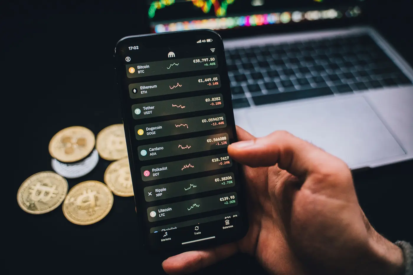 A phone showing crypto prices beside a laptop